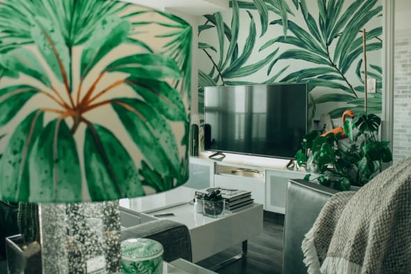 Tropical-inspired living room with green wallpaper and neutral-toned TV furniture