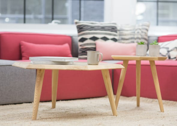 Two light wood coffee tables in front of red and gray sofa in a cozy modern living room.