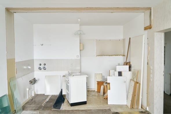 Empty kitchen space with old appliences, exposed walls, and dismantled furniture pieces ready for renovation.